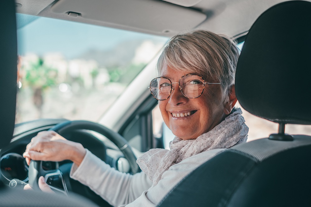 Happy owner. Handsome mature woman sitting relaxed in his newly bought car looking at the camera smiling joyfully. One old senior driving and having fun.